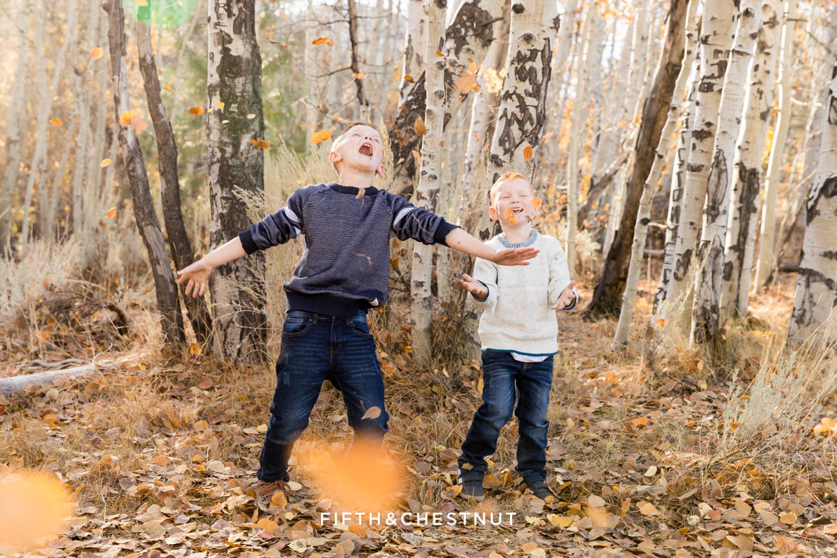 Two boys go wild with fall leaves during their Thomas Creek family photos by Reno Family Photographer.