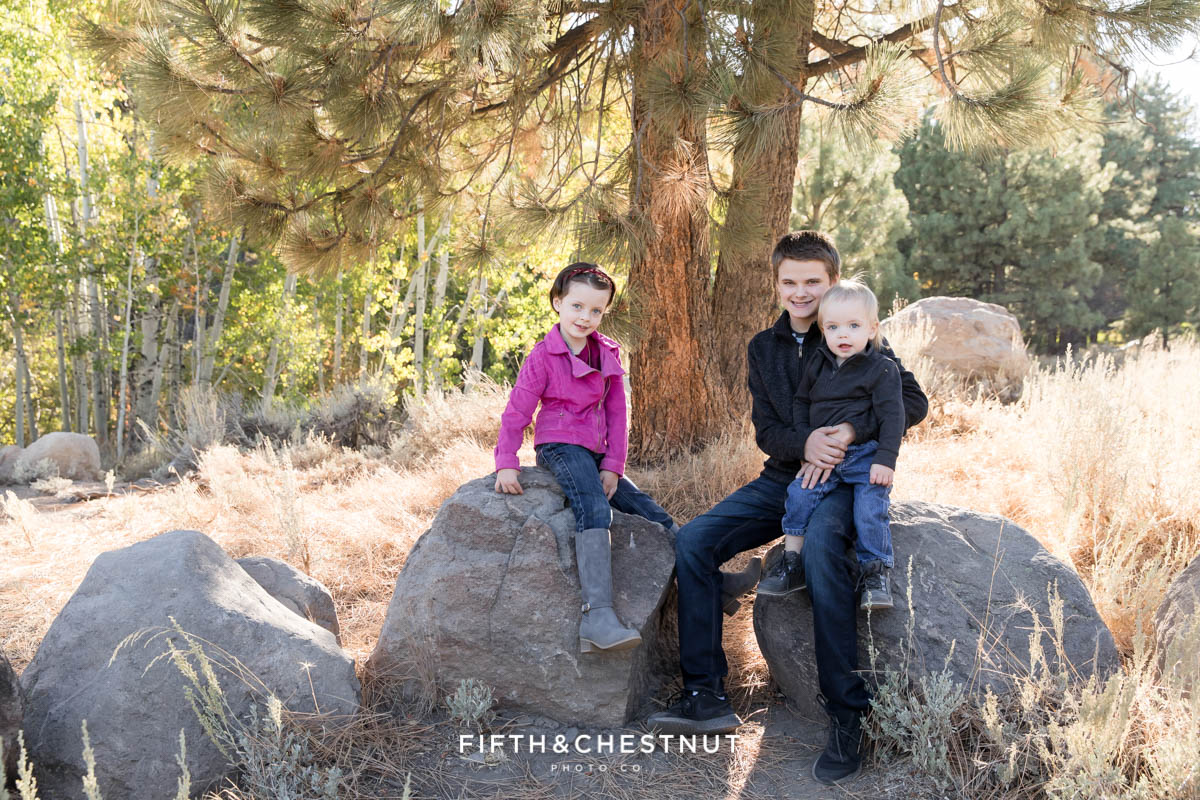 Three siblings sit on rocks together for Thomas Creek Portraits near the popular trailhead.