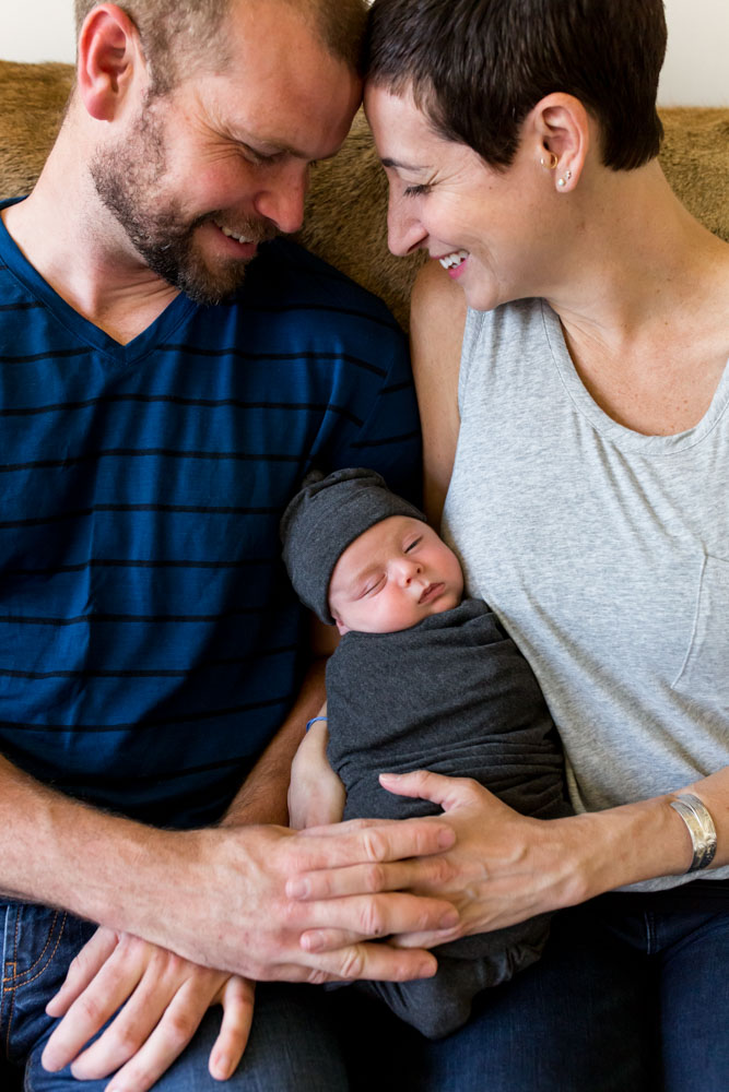 A mom and dad smile with joy as they hold their newborn baby boy for portraits by Reno Newborn Photographer Fifth and Chestnut Photo Co.
