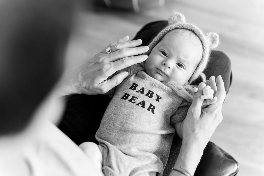 black and white image of a newborn baby boy wearing a "baby bear" onesie and a bear hat for lifestyle newborn photos by Reno Newborn Photographer