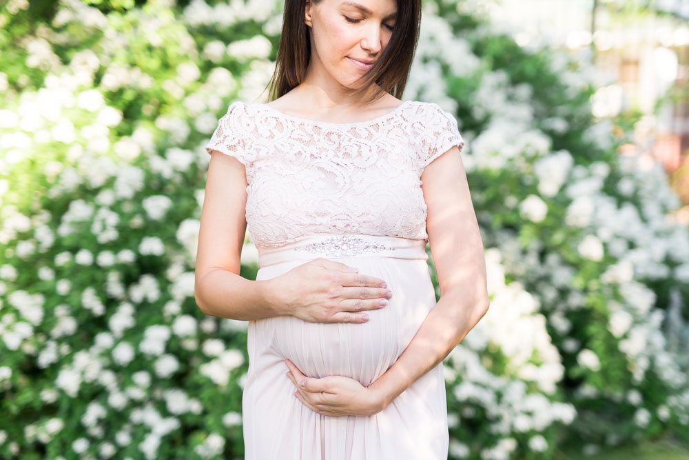 Spring Reno Maternity Photo with white roses in background and mom-to-be in blush dress.
