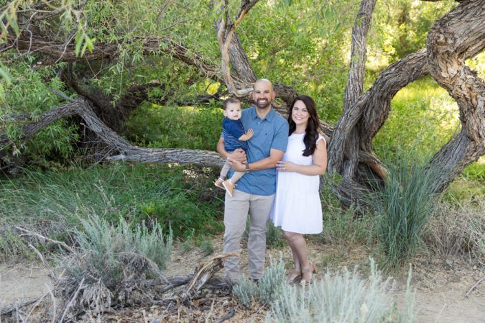 Family of three stands in a lush high desert landscape for their Reno family portraits by Reno Family Photographer