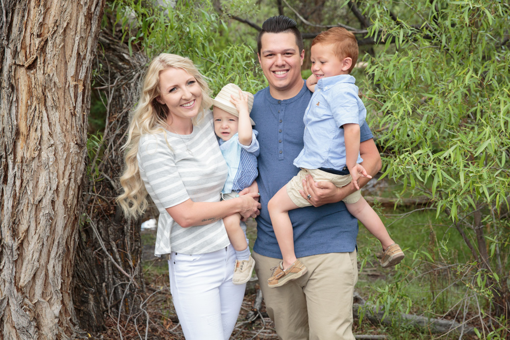 A mom and dad plus their two boys smile and laugh for a photo by a Reno Family Photographer at Evan's Creek trail in Reno
