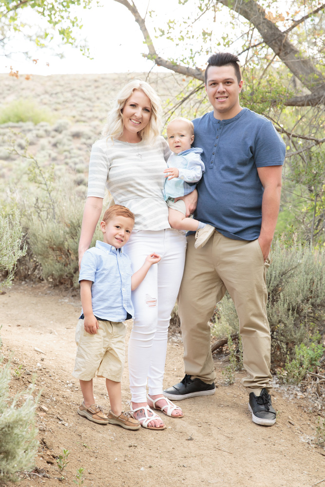Gorgeous family of four stands on a trail at Evan's Creek trailhead in Reno wearing shades of blue, white and khaki for a family photo by Reno Family Photographer Fifth and Chestnut Photo Co.