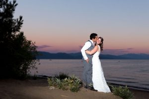 Bride and groom snuggle on the beach of North Lake Tahoe in King's Beach for a sunset photo by Tahoe Photographer