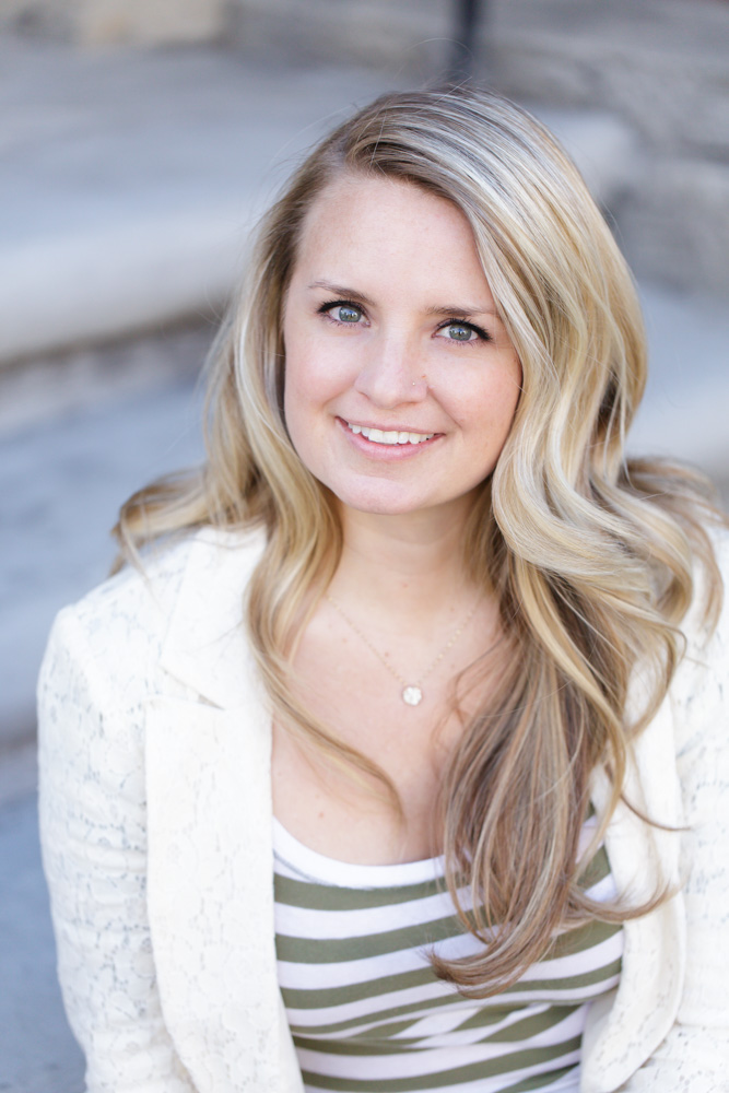 A gorgeous professional headshot of a blonde woman wearing a white and green striped shirt with a white blazer sitting on concrete steps for her Reno Headshots by Reno Headshot Photographer