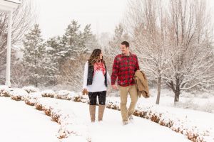 Pregnant couple walks down a snow-covered path at the Old Huffaker School House at Bartley Ranch in Reno for their snowy Reno maternity photos by Reno maternity photographer