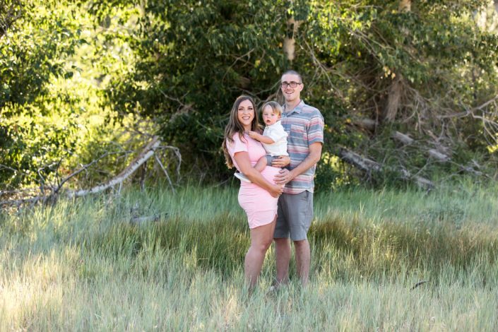 Family poses in a field for Reno Maternity Photos by Reno Maternity Photographer while expecting their second baby