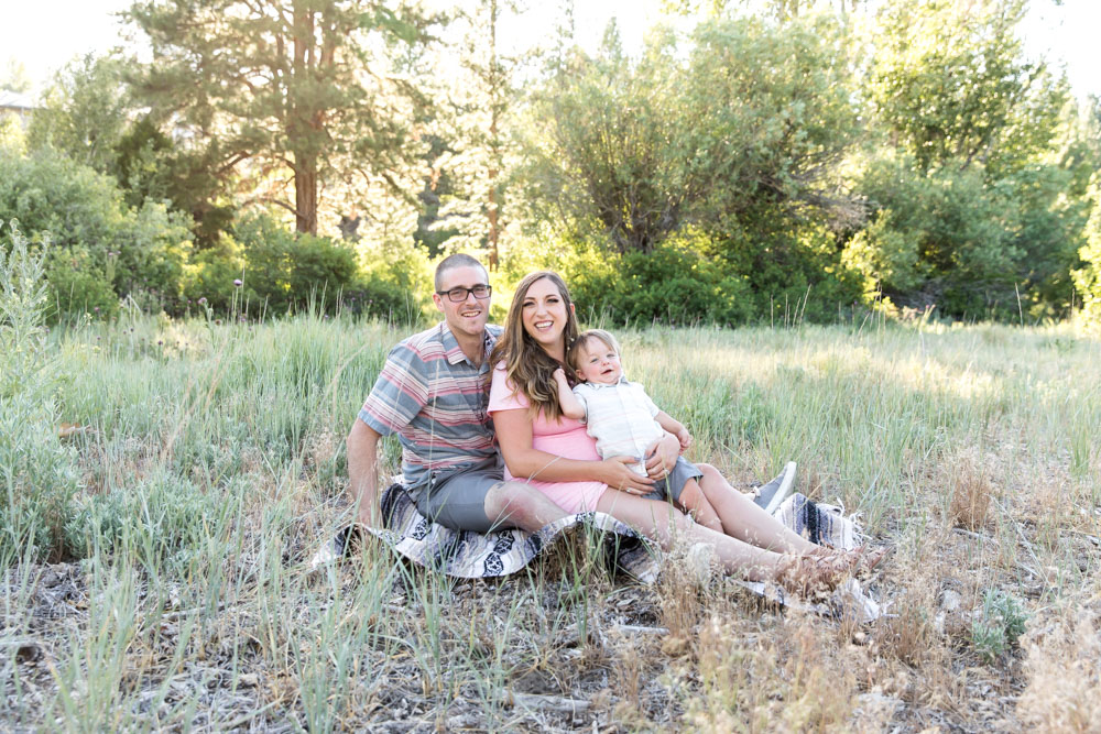 Family poses in a field on a blanket for Reno Maternity Photos by Reno Maternity Photographer while expecting their second baby