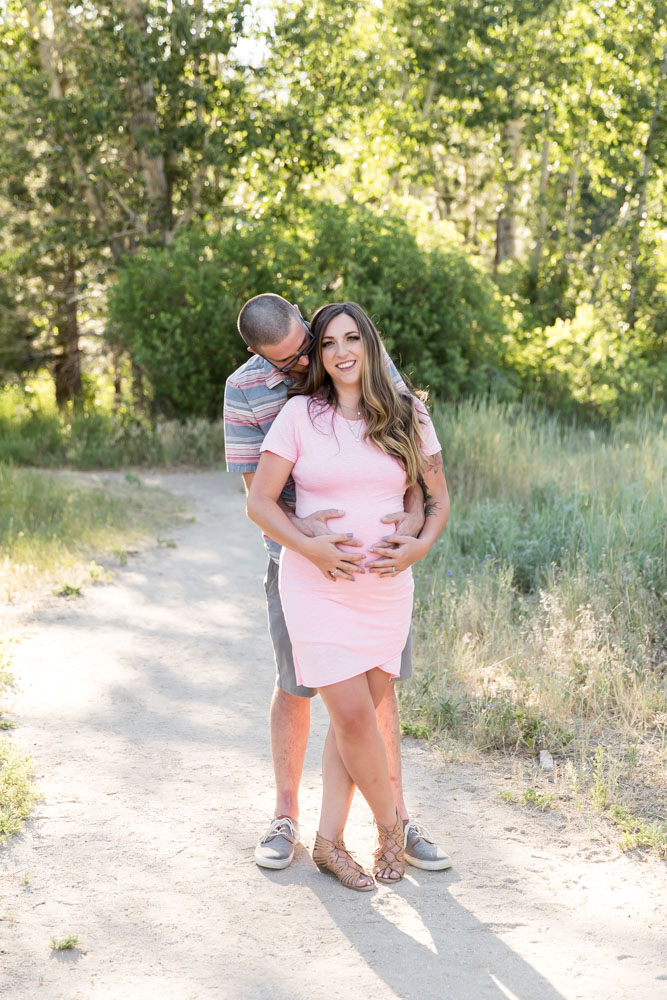 Husband holds his pregnant wife in a beautiful lush location for reno maternity photos with Reno Maternity Photographer