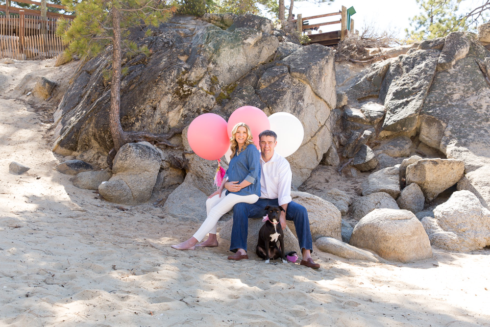 Mom, dad and dog with balloons pose for sunny spring maternity photos at Sand Harbor in Lake Tahoe by Lake Tahoe Maternity Photograhpher