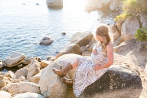 Mother to be sits on rocks at Sand Harbor for Tahoe Maternity Photos