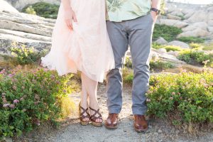 Photo of couple's lower halves showing their personalities with their outfits and shoes. female is wearing a pink tulle skirt and high heel shoes while male has gray pants and brown dress shoes