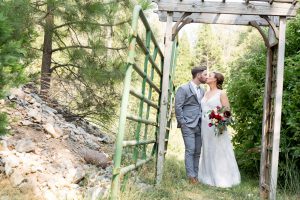 bride and groom kiss under an old arbor for their Greenhorn Creek Guest Ranch Wedding
