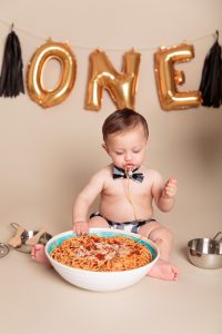 Baby boy eating spaghetti during his One Year Spaghetti Smash portrait session by Reno Baby Photographer