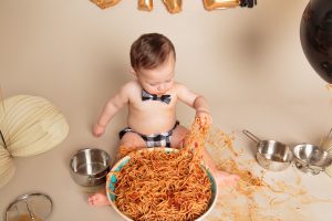 Baby boy digging into giant bowl of spaghetti for his One Year Spaghetti Smash portrait session by Reno Baby Photographer