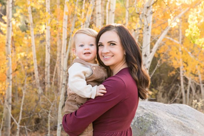 A mom wearing burgundy holds her sweet baby boy for a Reno fall family portrait at the Thomas Creek Trailhead by Reno Family Photographer
