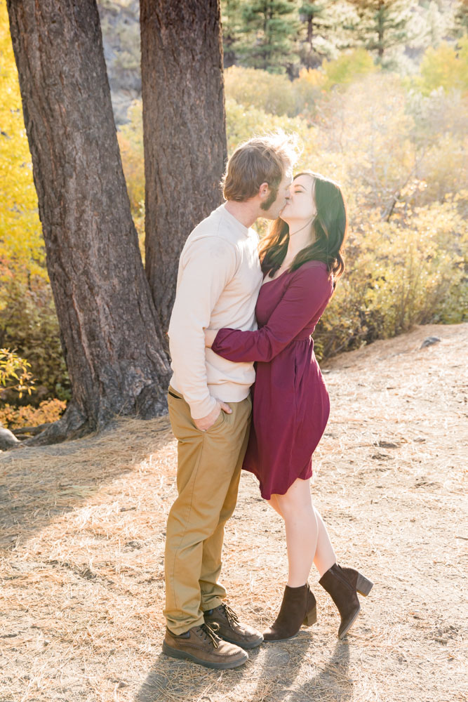 A couple kisses as the sun shines behind them for their Reno fall family portraits