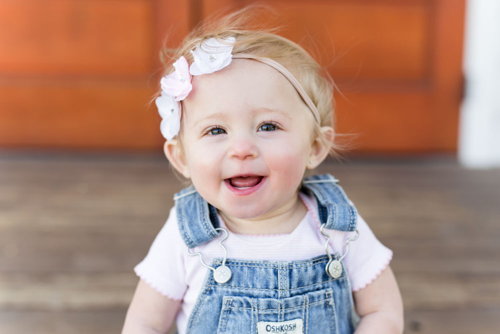 a happy and smiling baby girl laughs while having her reno one year photos done by reno child photographer at bartley ranch