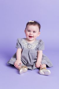 Sitter session with baby girl in gray dress on purple background