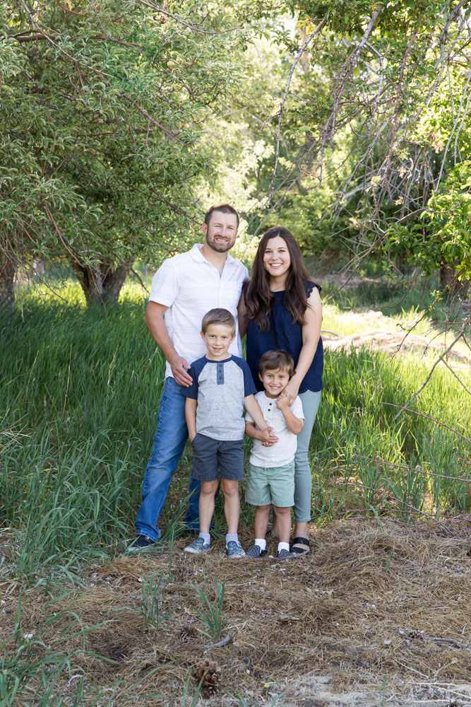 A family of four huddles together in a lush summer meadow for Reno Family Portraits by Reno Family Photographer