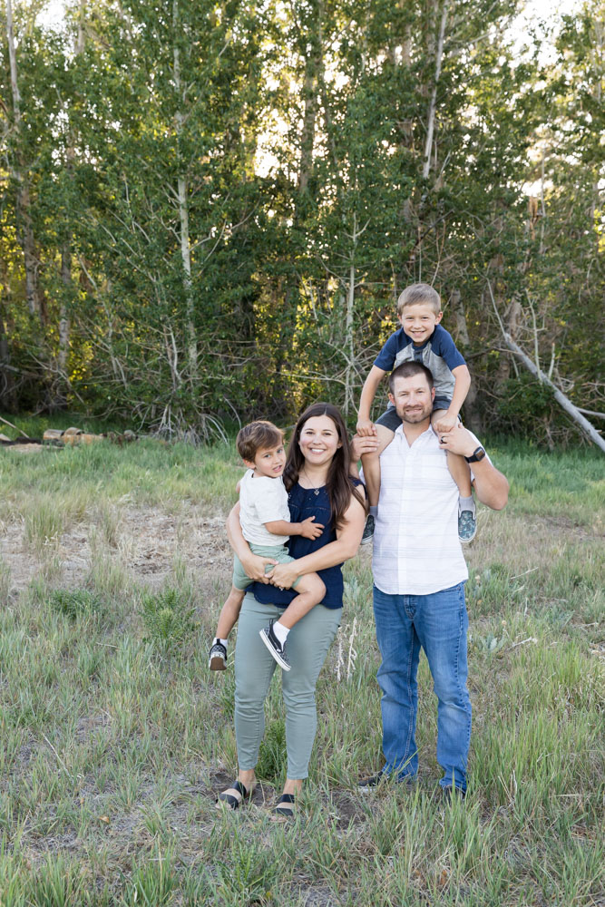 A family of four snuggles together in a lush summer meadow for Reno Family Portraits by Reno Family Photographer