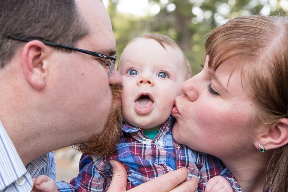 parents kiss baby boy on cheeks during their family photos at galena creek park by reno family photographer