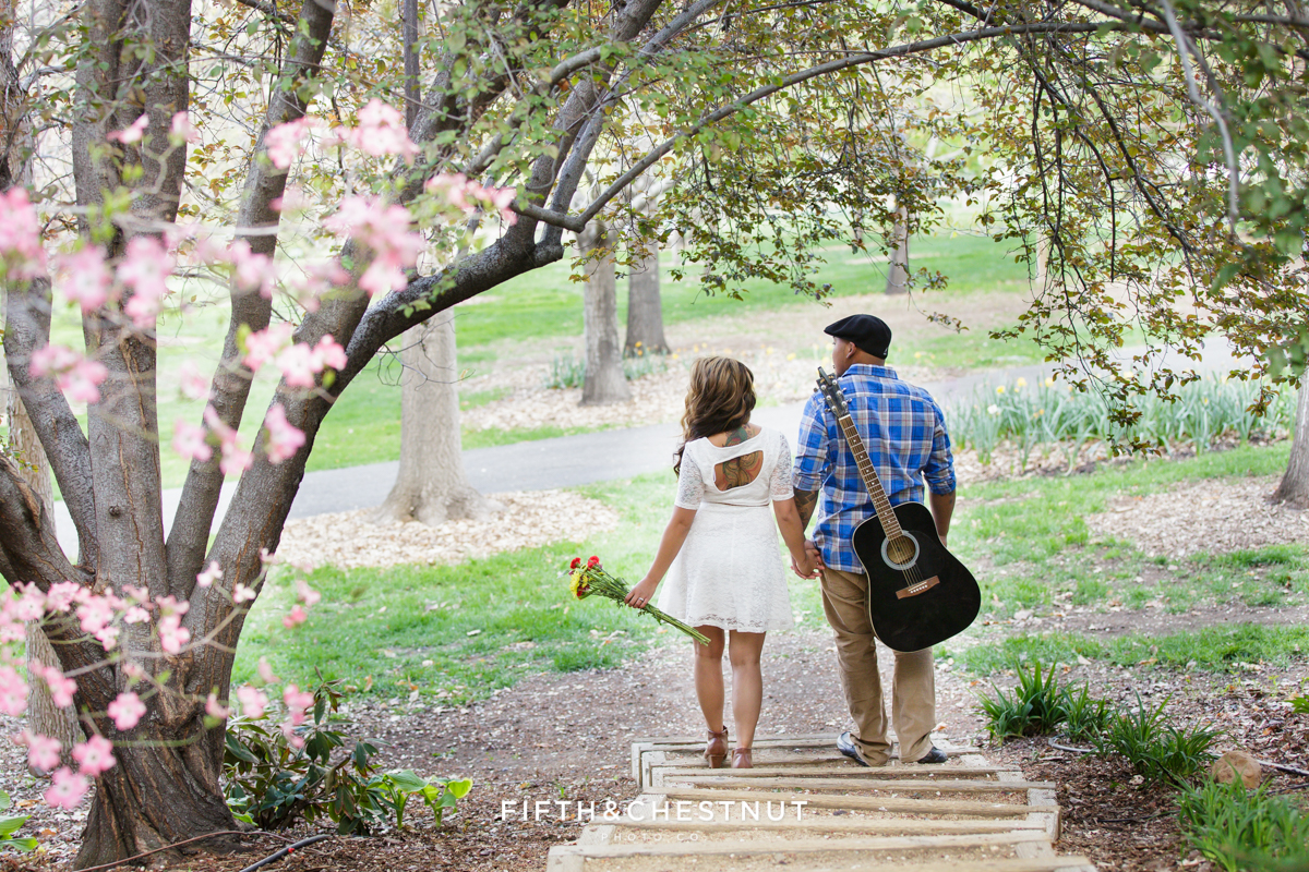 A couple walks under a gorgeous dogwood tree at Rancho San Rafael for family portraits by Reno Family Photographer