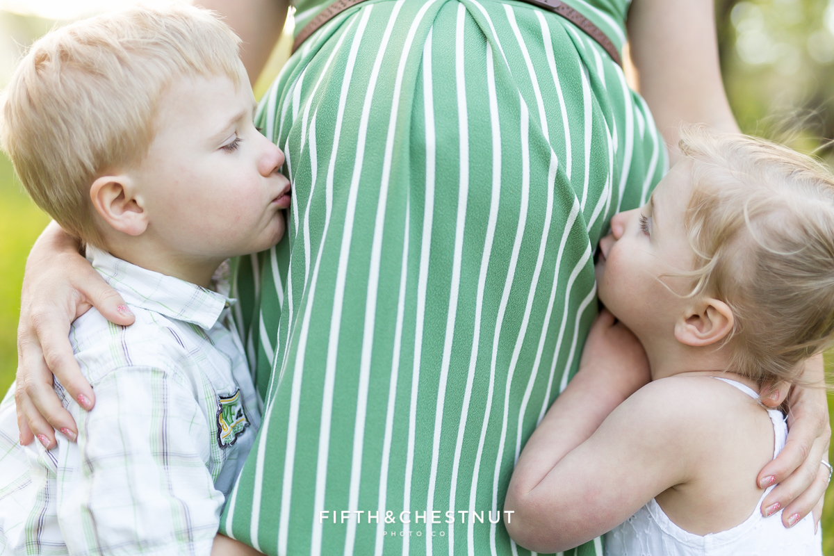 Older brother and sister give new baby bump kissed for a maternity photography session in reno