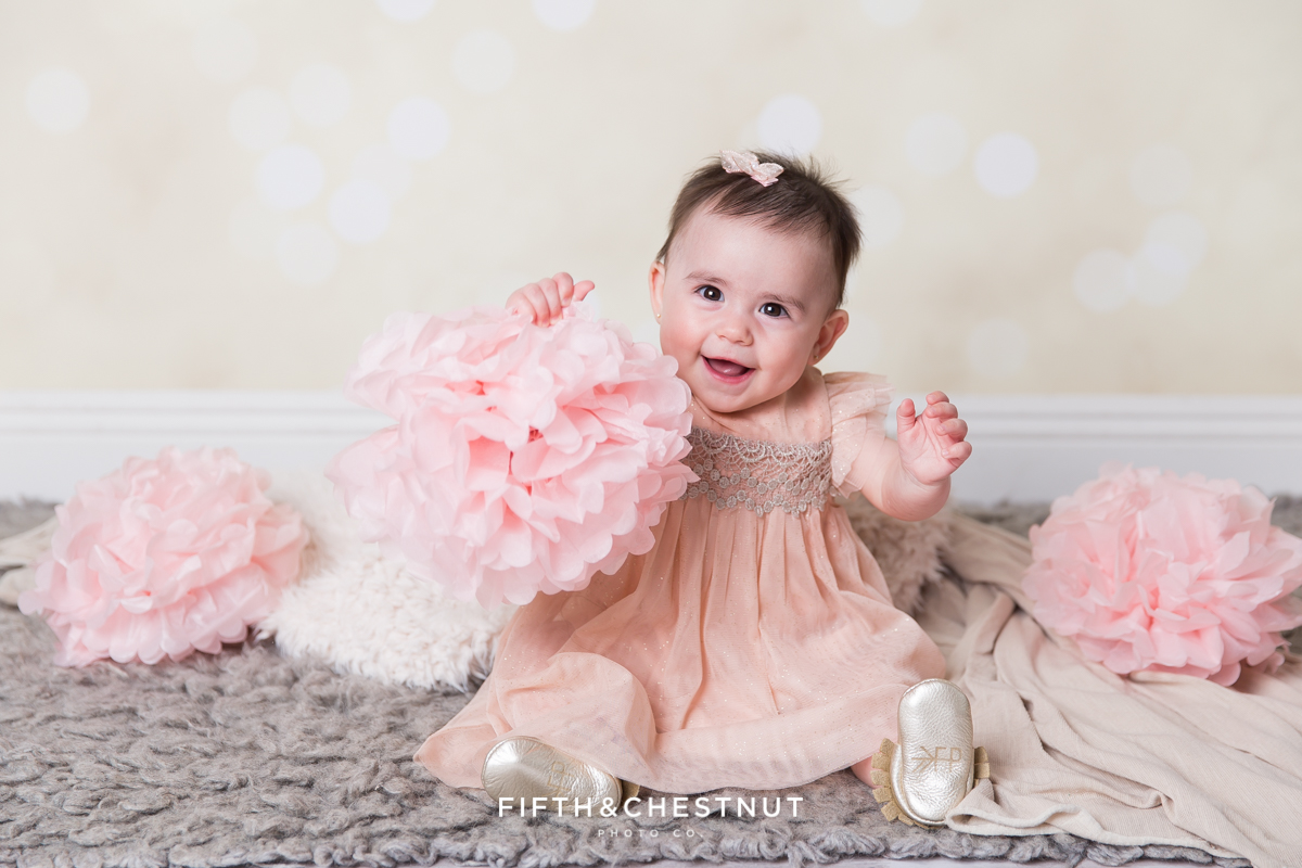 Baby Girl playing with a paper flower and wearing a glittery pink dress for portraits by Reno Baby Photographer Fifth and Chestnut