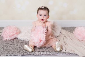 Baby Girl smiling and wearing a glittery pink dress for portraits by Reno Baby Photographer Fifth and Chestnut