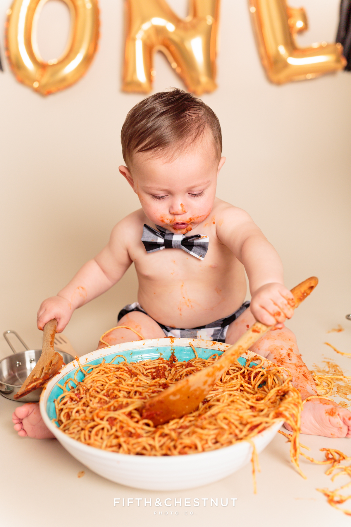 baby boy digging into ginormous bowl of spaghetti for a one year spaghetti smash portrait session with Reno baby photographer