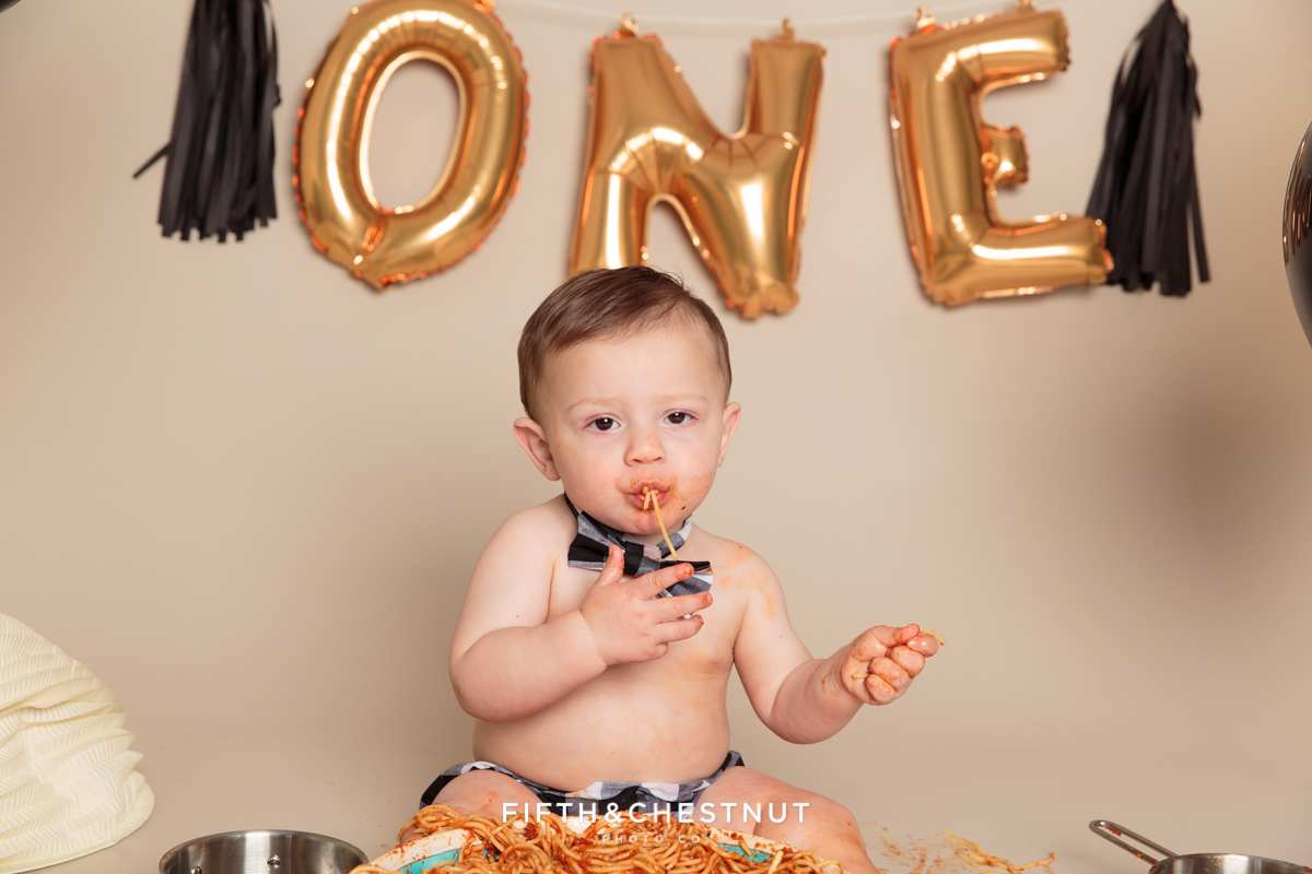 one year old boy eating spaghetti out of a giant bowl for his one year spaghetti smash session