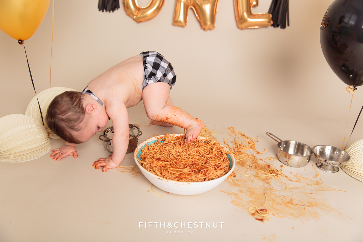 baby boy stepping into his giant spaghetti bowl after his one year spaghetti smash toddler portraits