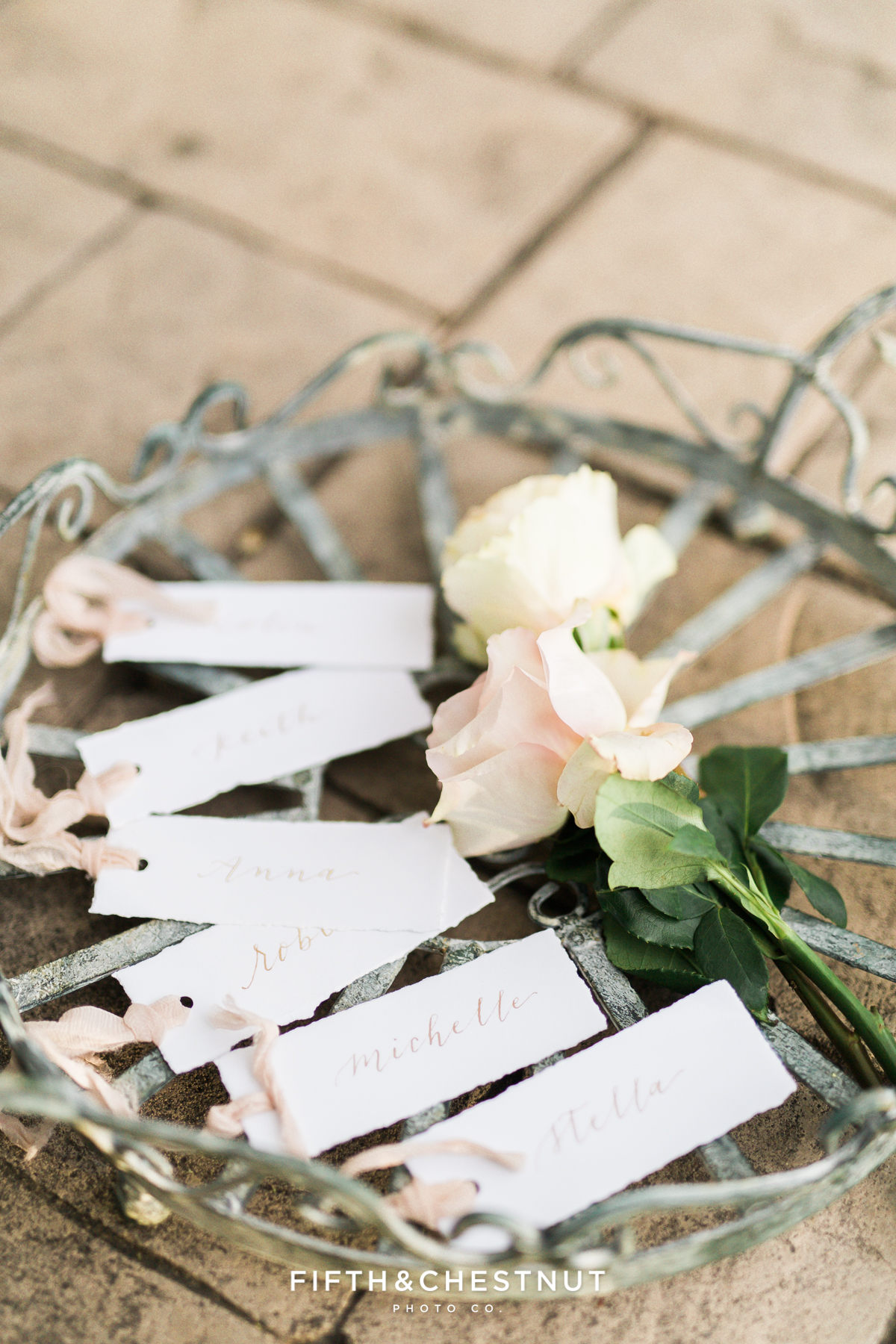 Escort cards on a vintage tray with roses for a Dusty Blue Private Estate Country French Wedding Styled Shoot