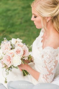 Beautiufl blonde bride looking at her wedding bouquet by Aster and Ash for a dusty blue styled shoot in Reno, NV