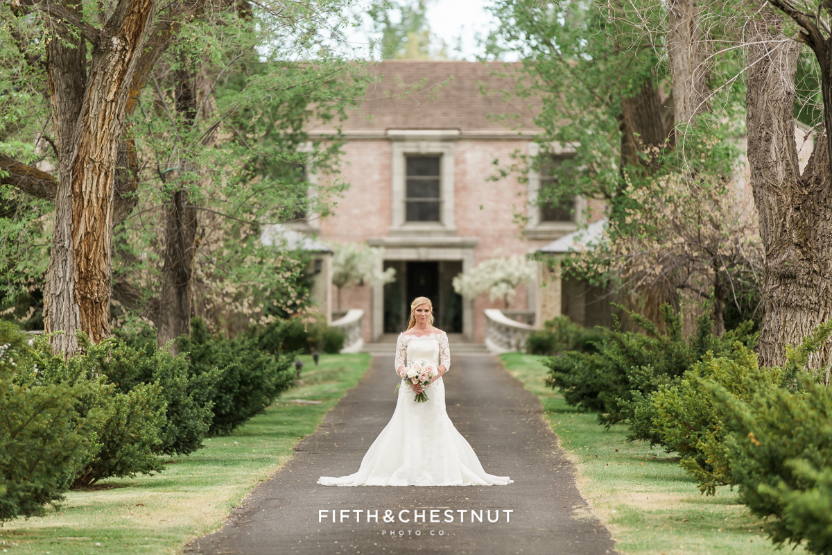 Bride standing in oak-lined path leading to an elegant private estate