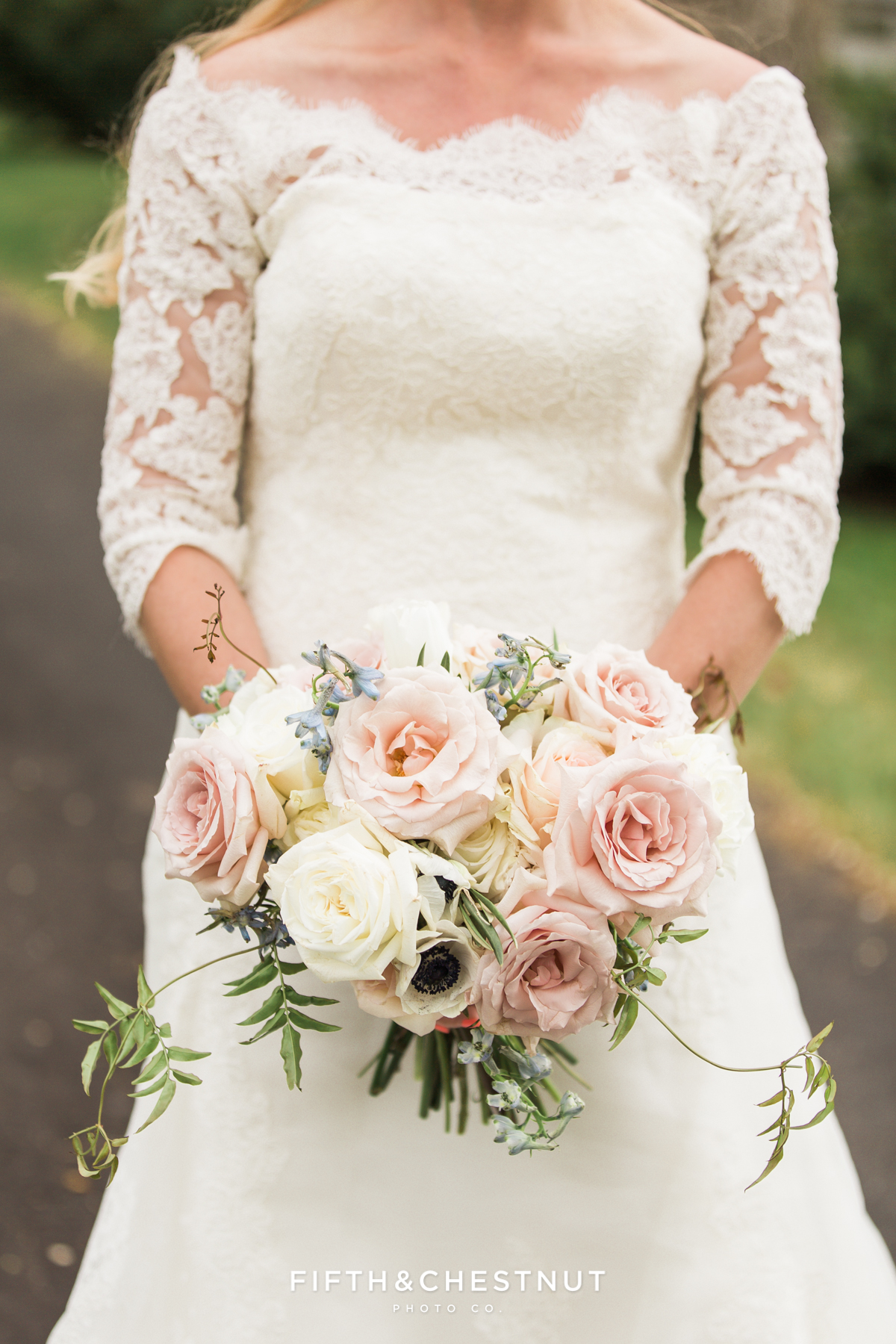 Bride in a lace wedding dress showing off her country french bouquet for a dusty blue wedding styled shoot