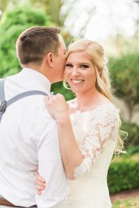 Groom whispering sweet nothings into his brides ear as she smiles and laughs