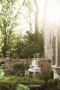 Sun peeking behind brick estate showing a dusty blue and white ombre watercolor wedding cake on a vintage white vanity table for a dusty blue private estate country french wedding inspiration styled shoot by Lake Tahoe Wedding photographer