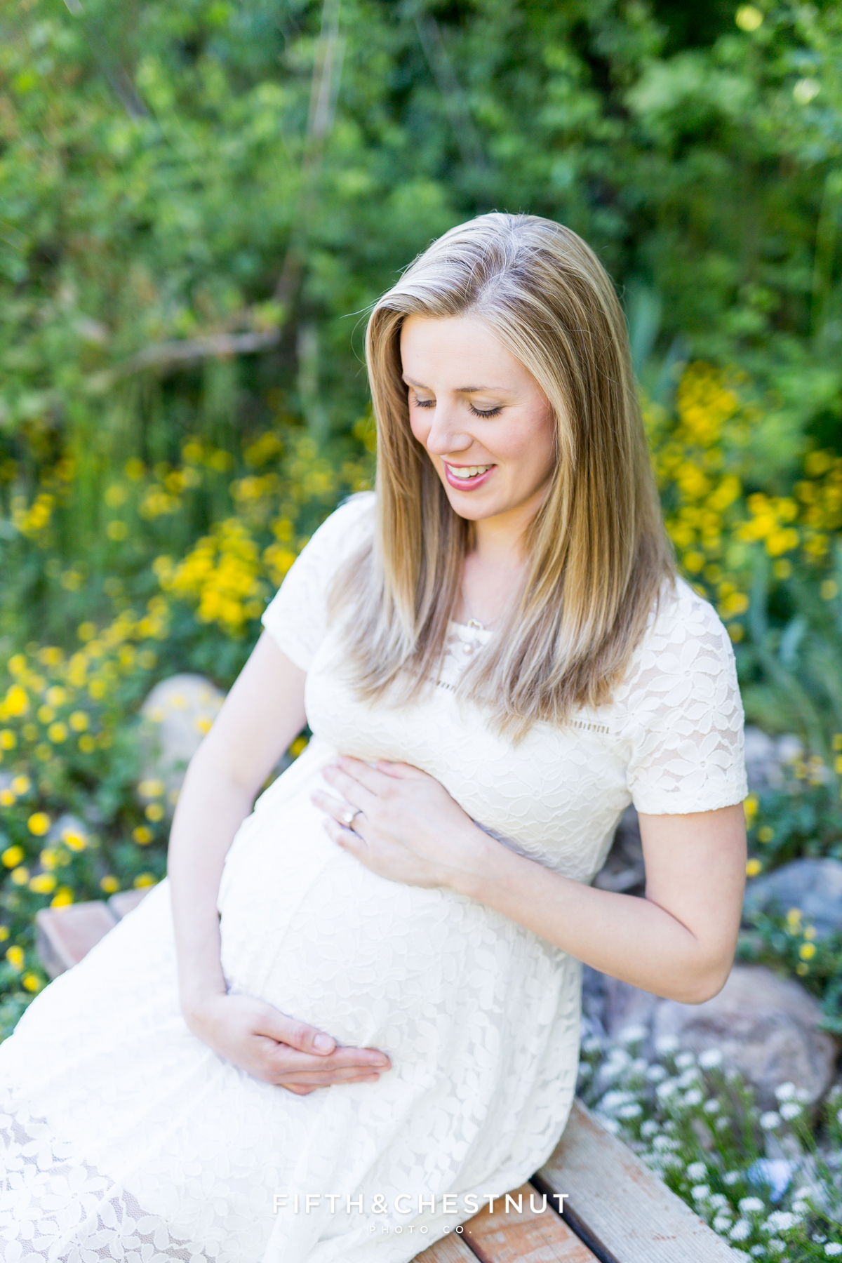Gorgeous blonde pregnant woman sitting on a bench looking at baby bump by Reno Maternity Photographer