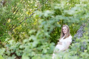 maternity portrait of woman leaning against a tree photographed through leaves at Rancho San Rafael Park