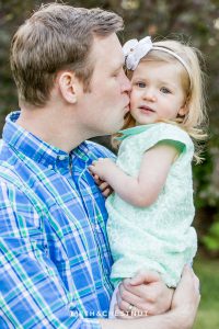 Dad gives two year old daughter a kiss on her cheek while being photographed at Rancho San Rafael by Reno Maternity Photographer