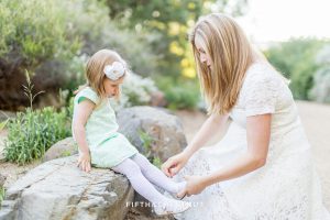 A pregnant mom fixes her toddler's shoes at a spring maternity photoshoot by Reno Maternity Photographer