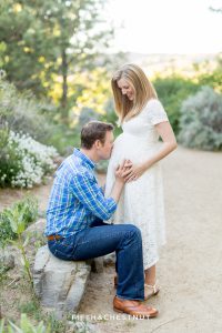 Husband kisses his wife's pregnant belly for spring reno maternity portraits by Reno maternity Photographer