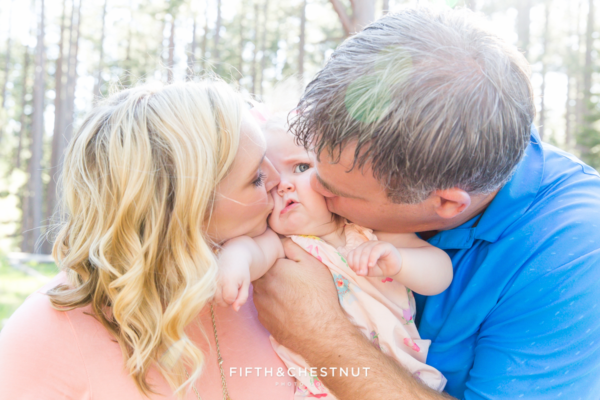 Mom and Dad kissing their one year old baby girl in Kiva Beach, Lake Tahoe for a family photoshoot by Lake Tahoe Family Photographer