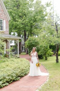 Bride laughs along brick path near the farm house at the Twenty Mile House before her boho chic wedding ceremony
