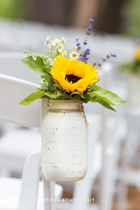 Sunflowers and other wild flowers in a white-painted mason jar with twine as wedding ceremony decor at the Twenty Mile House in Graeagle