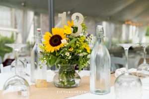 sunflower wedding arrangement, table number and vintage water bottles on a reception table for a Twenty Mile House wedding