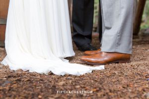 Detail photo of bride's dress and groom's brown leather shoes
